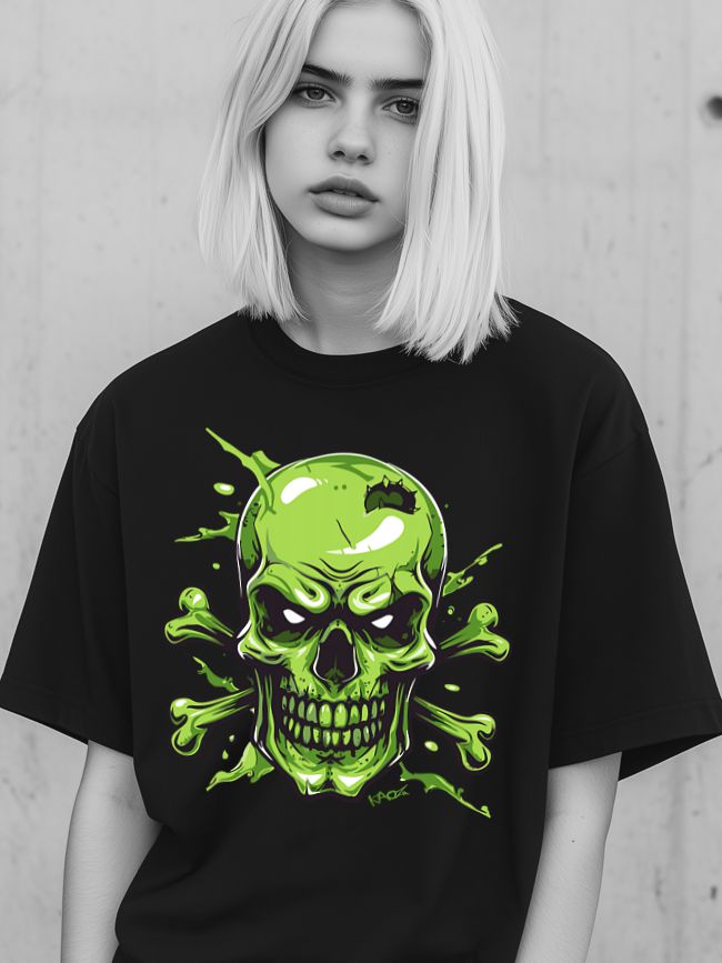 A young person with light blonde hair wearing a black oversized t-shirt with a vibrant green skull graphic, standing against a concrete wall.