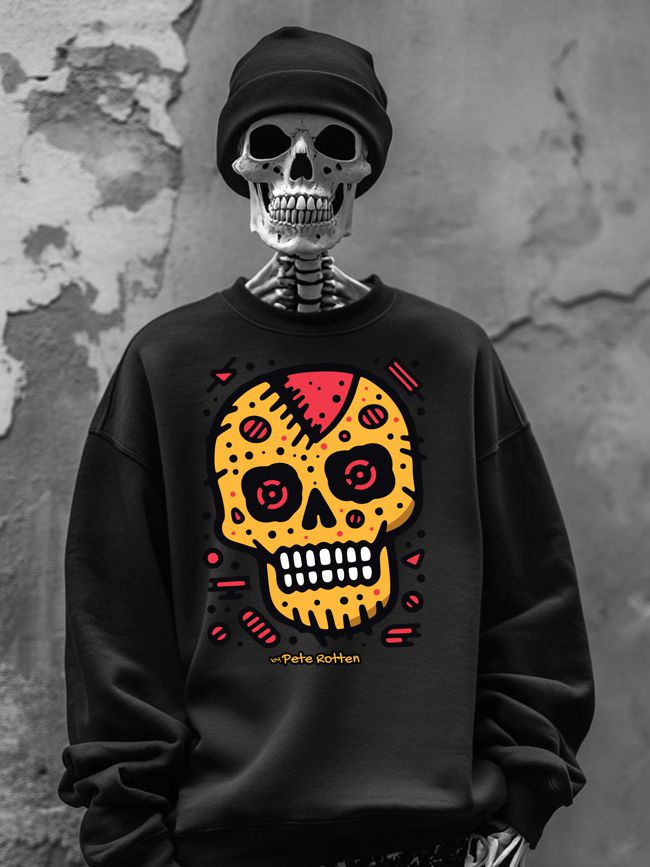 A skeleton wearing a black sweatshirt adorned with a colorful cookie skull design in yellow, red, and black, complemented by a black beanie, standing against a textured urban wall.