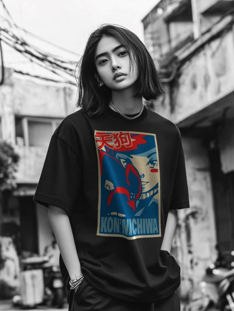 A young person with shoulder-length hair stands in a gritty urban environment wearing a black oversized t-shirt with a colorful KON'WICHIWA graphic design. The blurred cityscape in the background contrasts with the vibrant shirt.