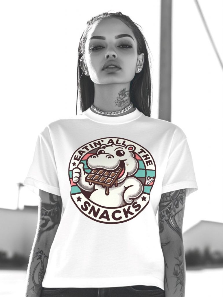 Black and white image of a confident individual wearing a white t-shirt with a cartoon hippo holding a chocolate bar and the text 'EATIN’ ALL THE SNACKS,' showcasing modern fashion and playful graphics.